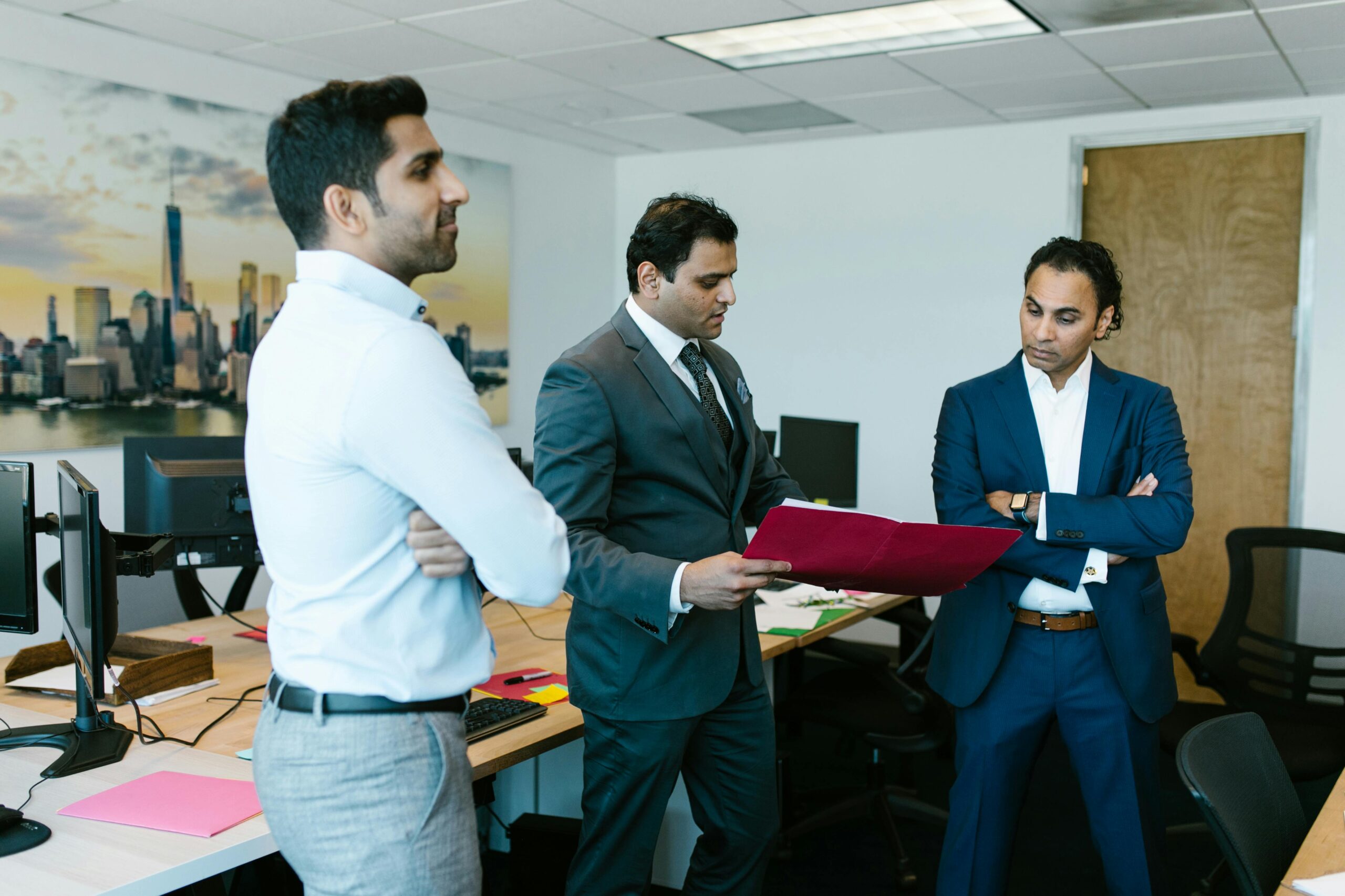 Three businessmen discussing important documents during a meeting in a modern office setting.